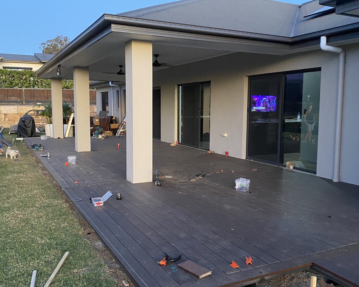 A large hardwood deck part-built at a modern home at dusk, with string lines and stakes set out