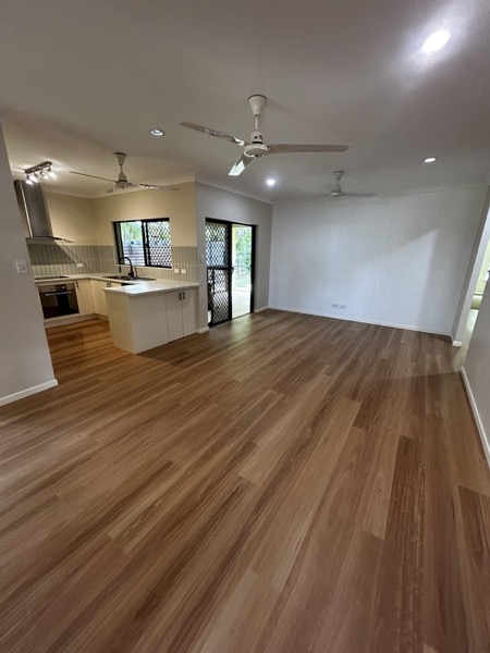 An open living room with new timber floorboards running through to the kitchen