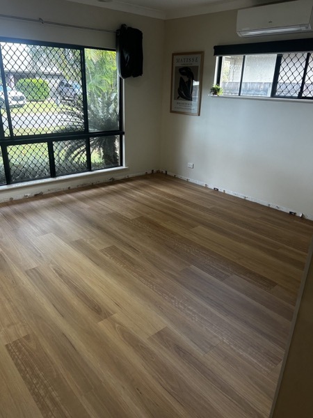 An empty room with new timber floorboards and windows to the garden