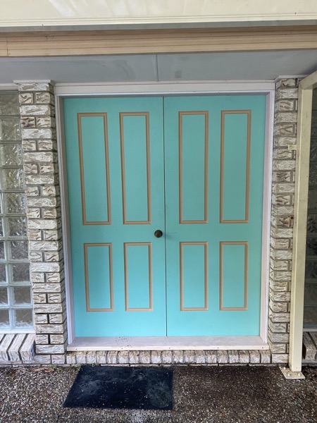 A pair of painted double entry doors set into a brick wall