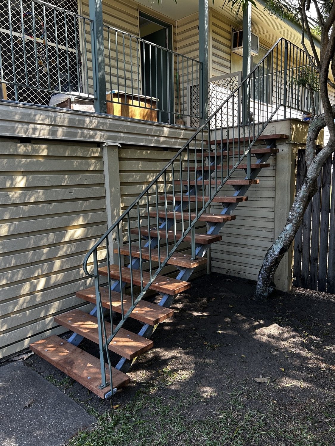An external steel and timber staircase running up the side of a raised home